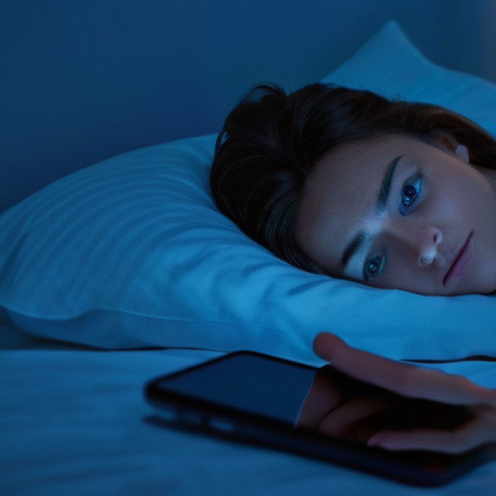 디지털 기기 사용과 스트레스 간의 상관관계 - A person lying in bed in a dimly lit room, illuminated by the blue light of a smartphone held close ...